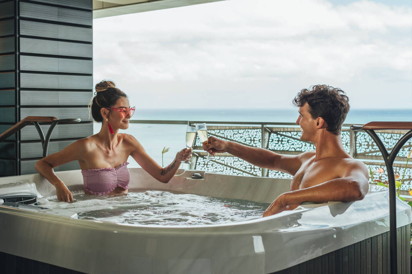 Couple drinking champagne and relaxing in Jacuzzi on balcony