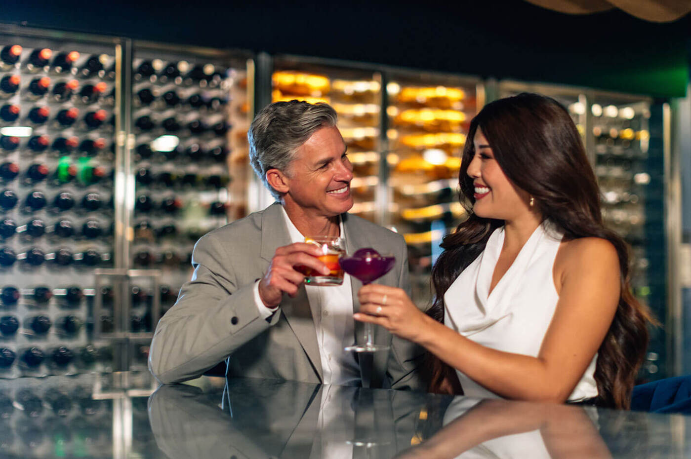 Couple enjoying drinks at bar with wine cellar in background