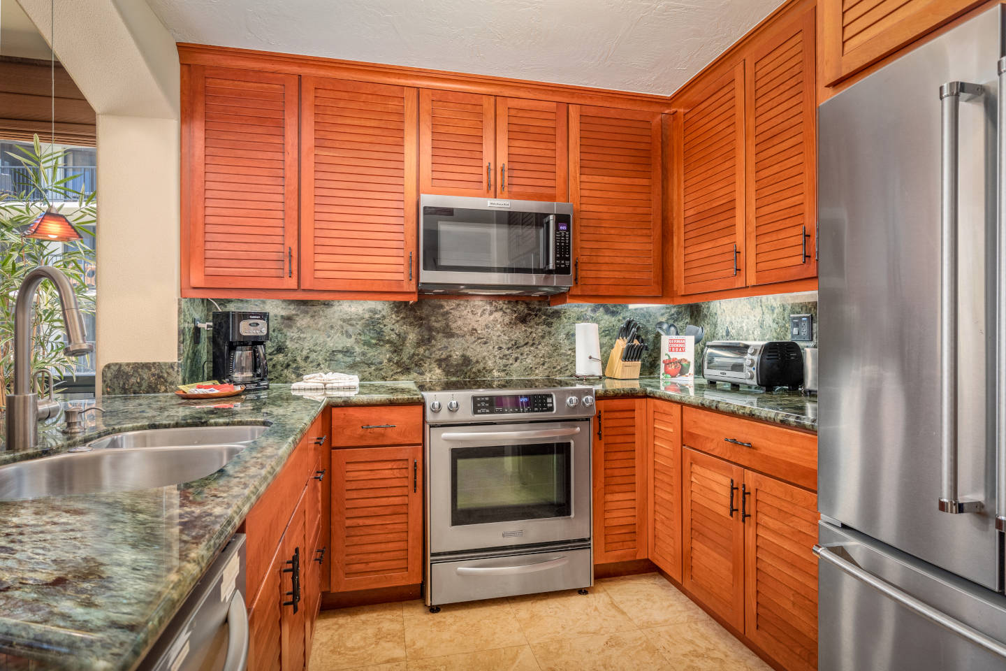Beautiful spacious updated kitchen with full-size appliances, stove/oven and a microwave above the stovetop, refrigerator and coffee maker and toaster oven on the marble countertop