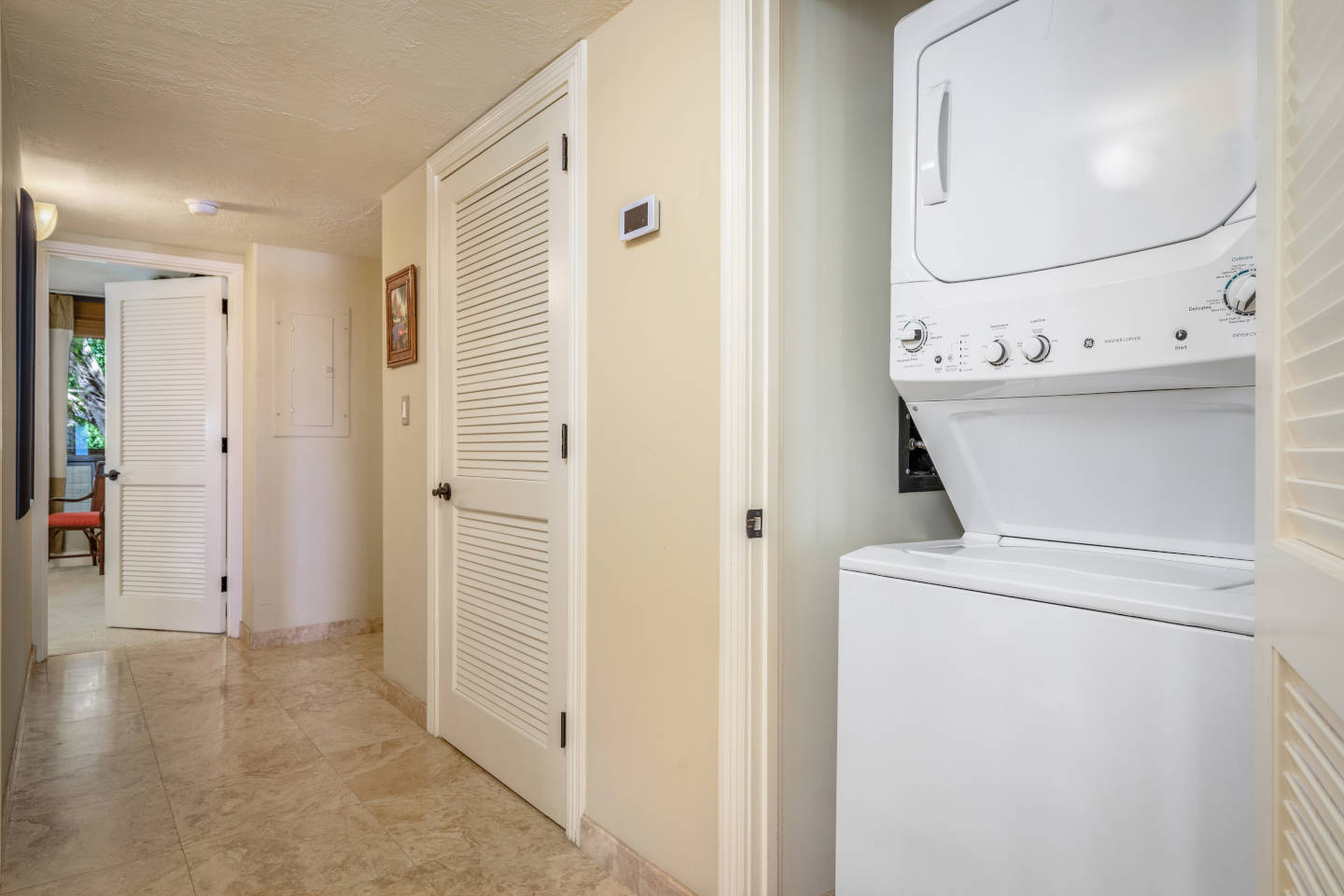 Standalone washer and dryer combo unit in-room that is tucked away in the hallway area of the one-bedroom oceanfront unit