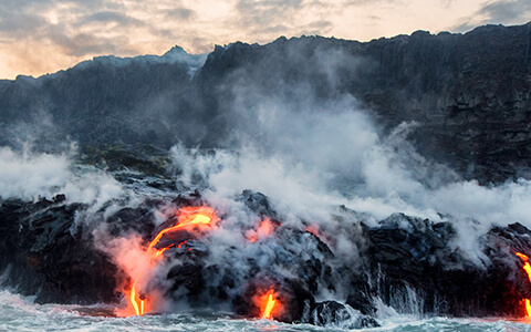 Volcano with lava flowing into ocean