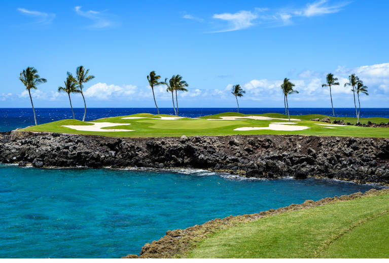 Golf course in Hawaii with ocean and palm trees
