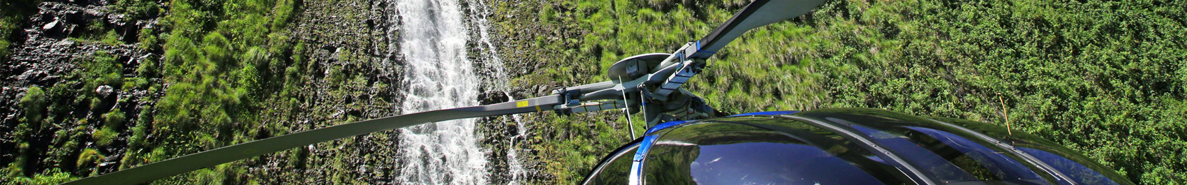 Helicopter flying next to a waterfall