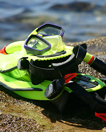 Snorkel gear sitting on a large rock next to the ocean.