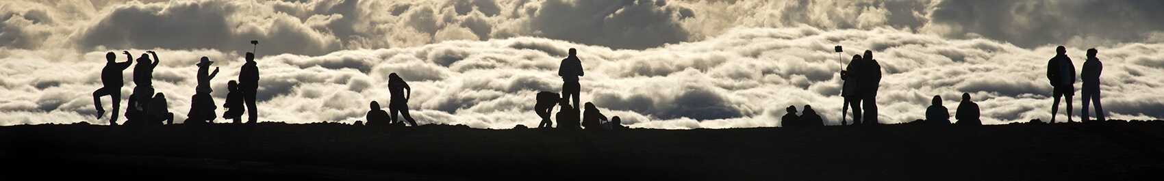 Silhouettes on mountain top against clouds
