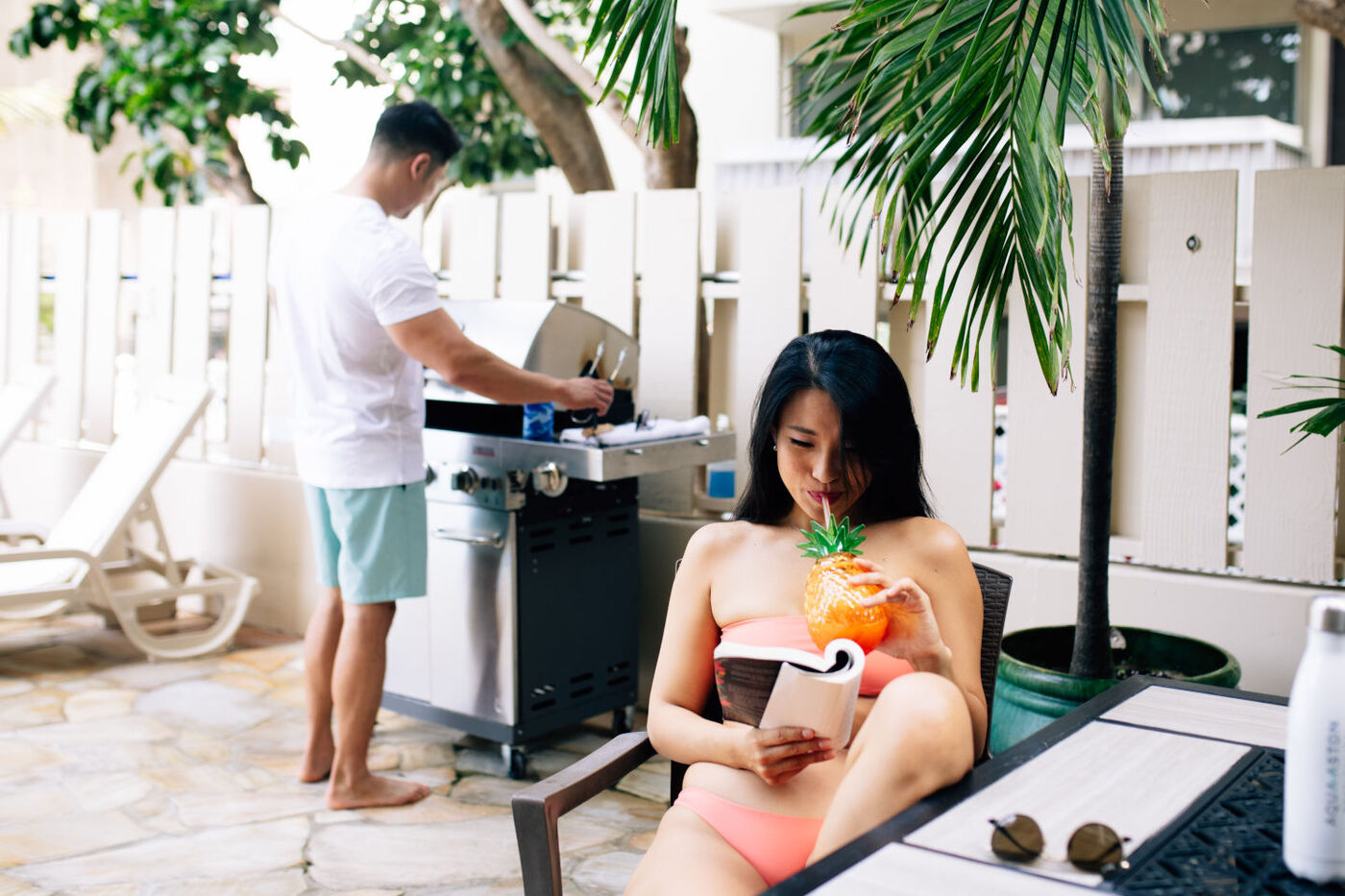 Man and woman enjoying outdoor barbecue grill and seating area near the pool