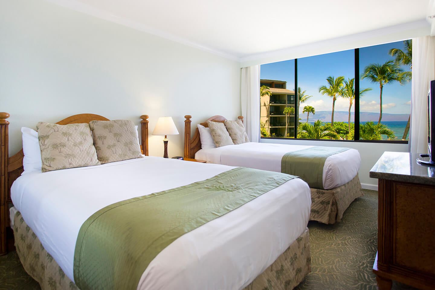 Room with 2 beds, lamp, TV, and large picture window.