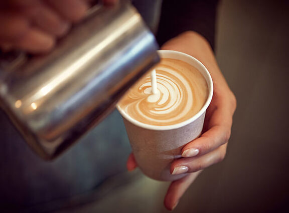 Close up of barista pouring coffee into to-go cup