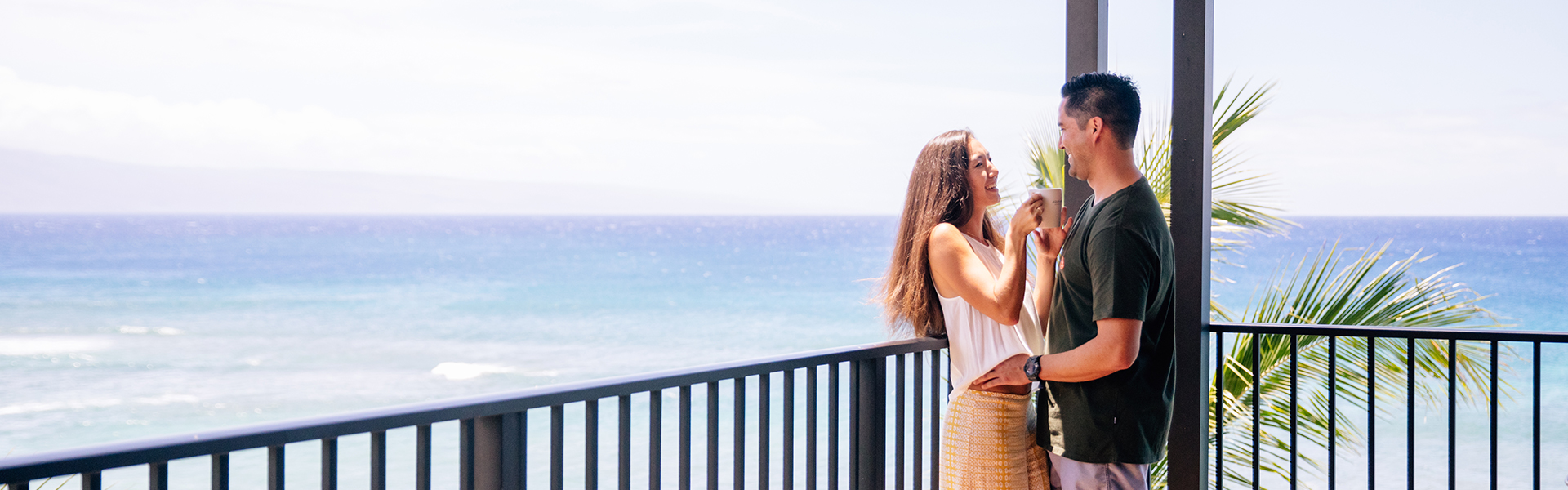 Couple on room balcony with ocean in the background