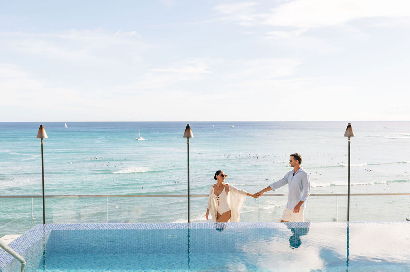 Couple walking along pool side with oceanfront views