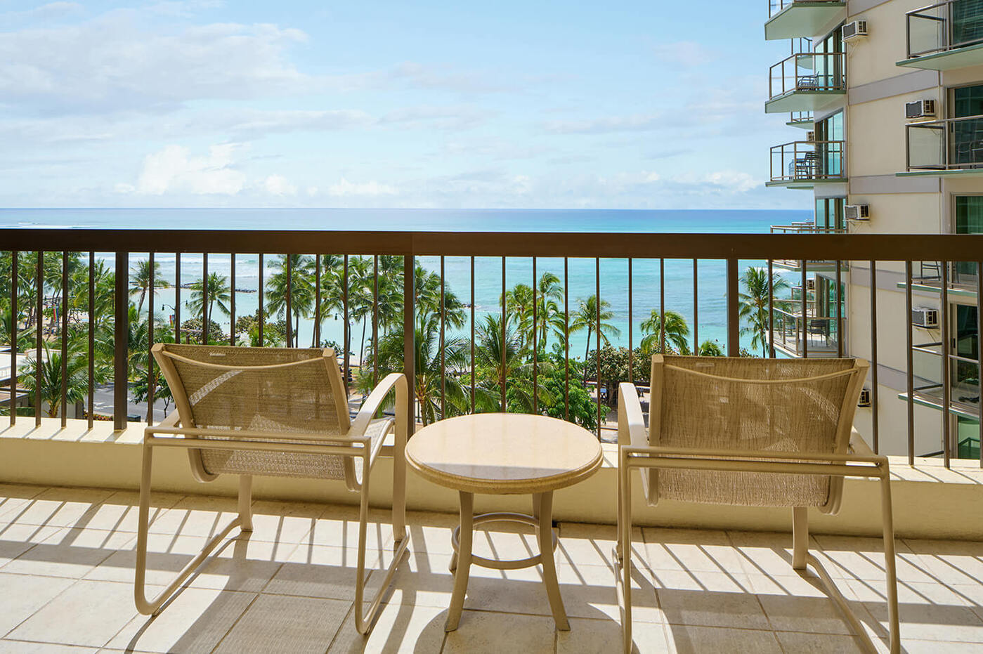 View of ocean from balcony with table and chairs