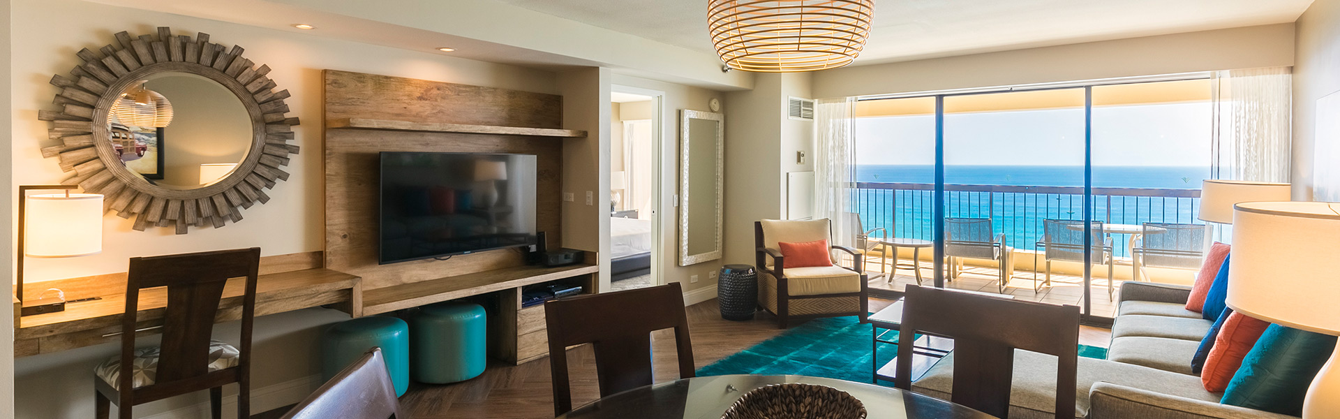 Guest suite living area with seating, TV, and balcony with view of ocean