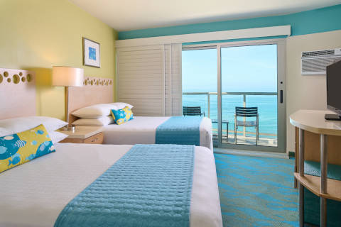 Oceanfront Deluxe Room with plantation shutters, double beds, balcony with seating to enjoy the Waikiki Beach view