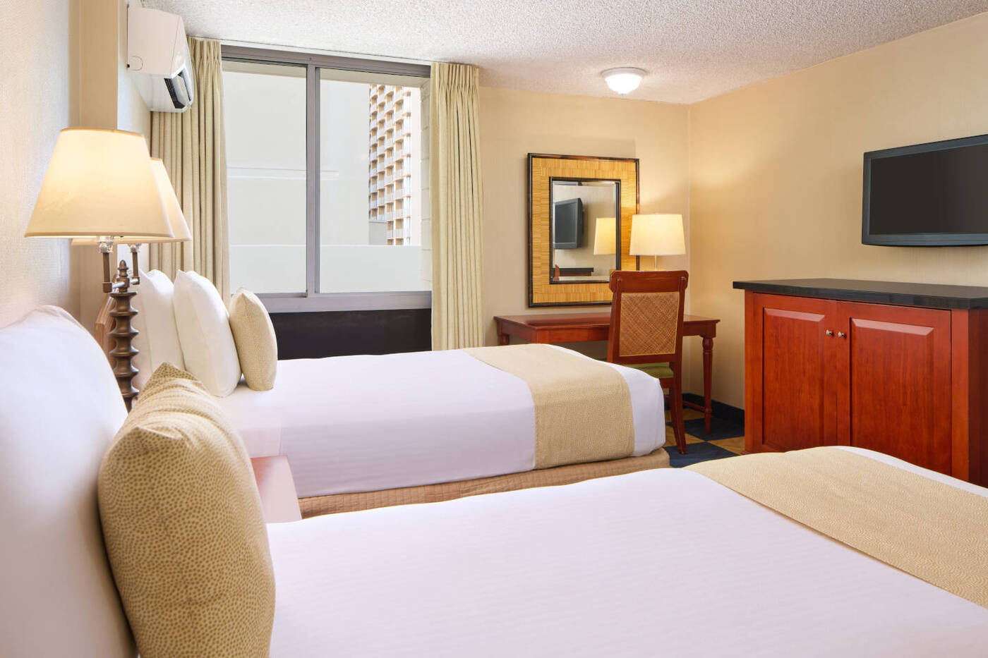 Moderate Hotel Room featuring a two-bed configuration that includes a desk and a television