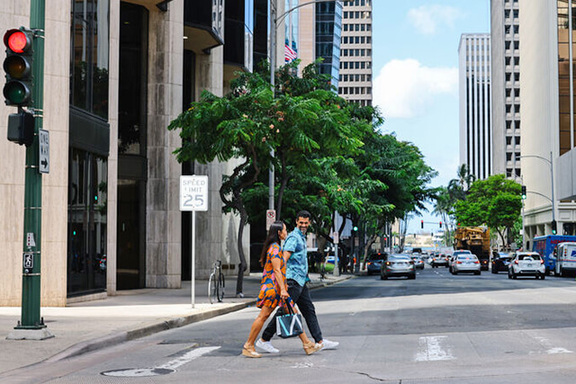 2 people walking across street in Downtown Honolulu