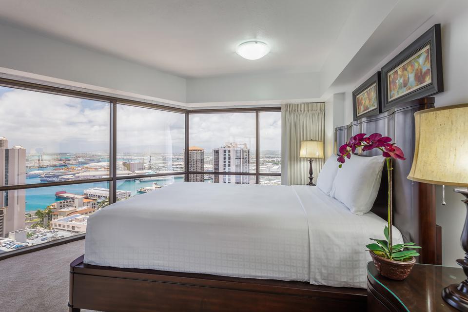 Oceanview bedroom with bed, view of the harbor, and Downtown Honolulu skyline at the Executive Center