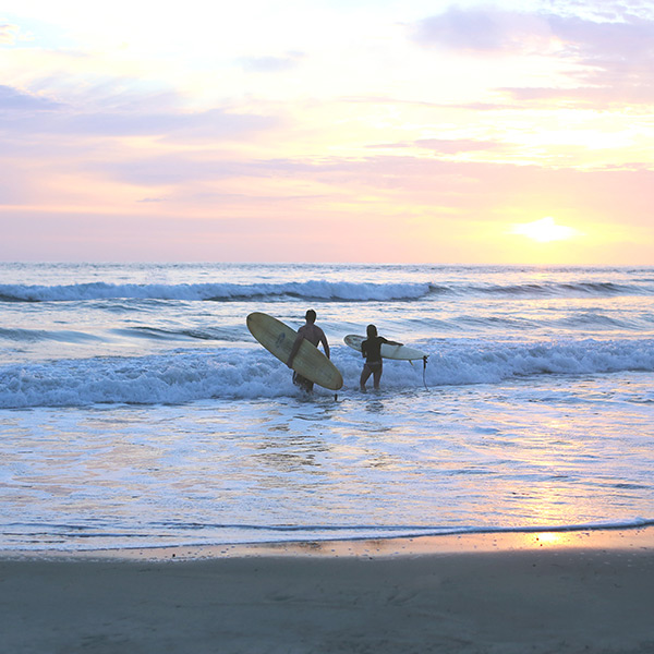 ハワイ・オアフ島のワイキキビーチで波に向かっていくサーファーカップル