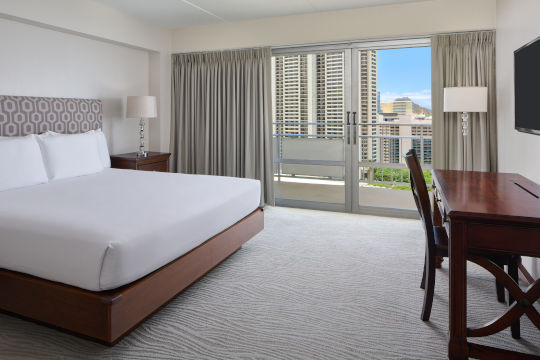 King bed in two bedroom ocean view suite with a nightstand, light fixtures and a desk 