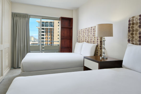 Second bedroom with two beds, night stand, light fixture in two bedroom ocean view suite 