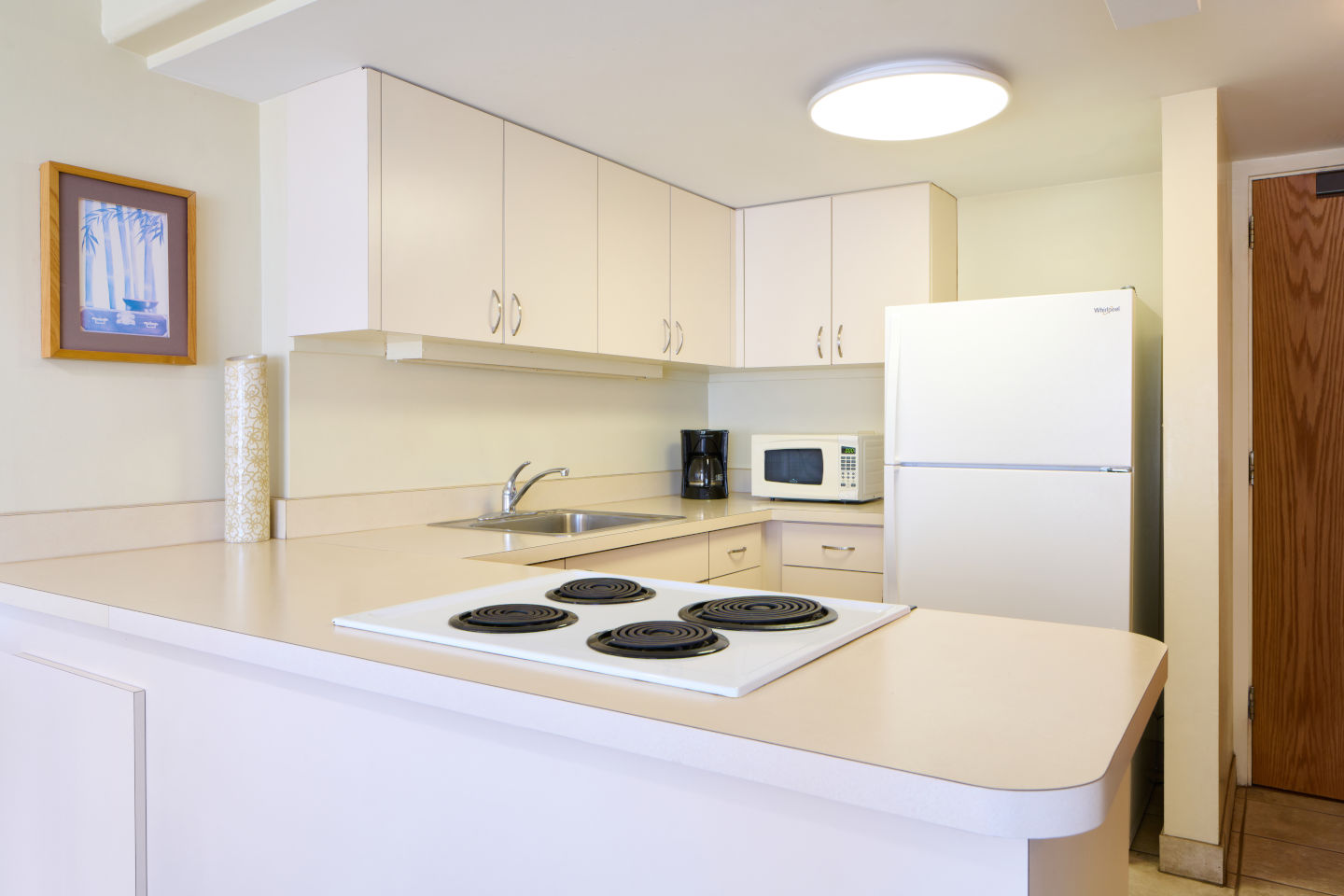 Full kitchen with a 4-burner stovetop and coffee maker, microwave, refrigerator, and lots of space to cook at the Ilikai Lite Ocean View Jr Suite 