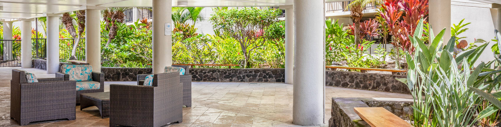 Spacious and open air lobby walkway with a sitting area and tropical plants 