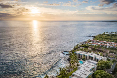 Drone view over the resort and ocean with the sun setting in the background