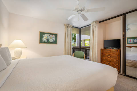One-Bedroom Ocean View Bedroom with a ceiling fan and lamp near the bed and a corner window