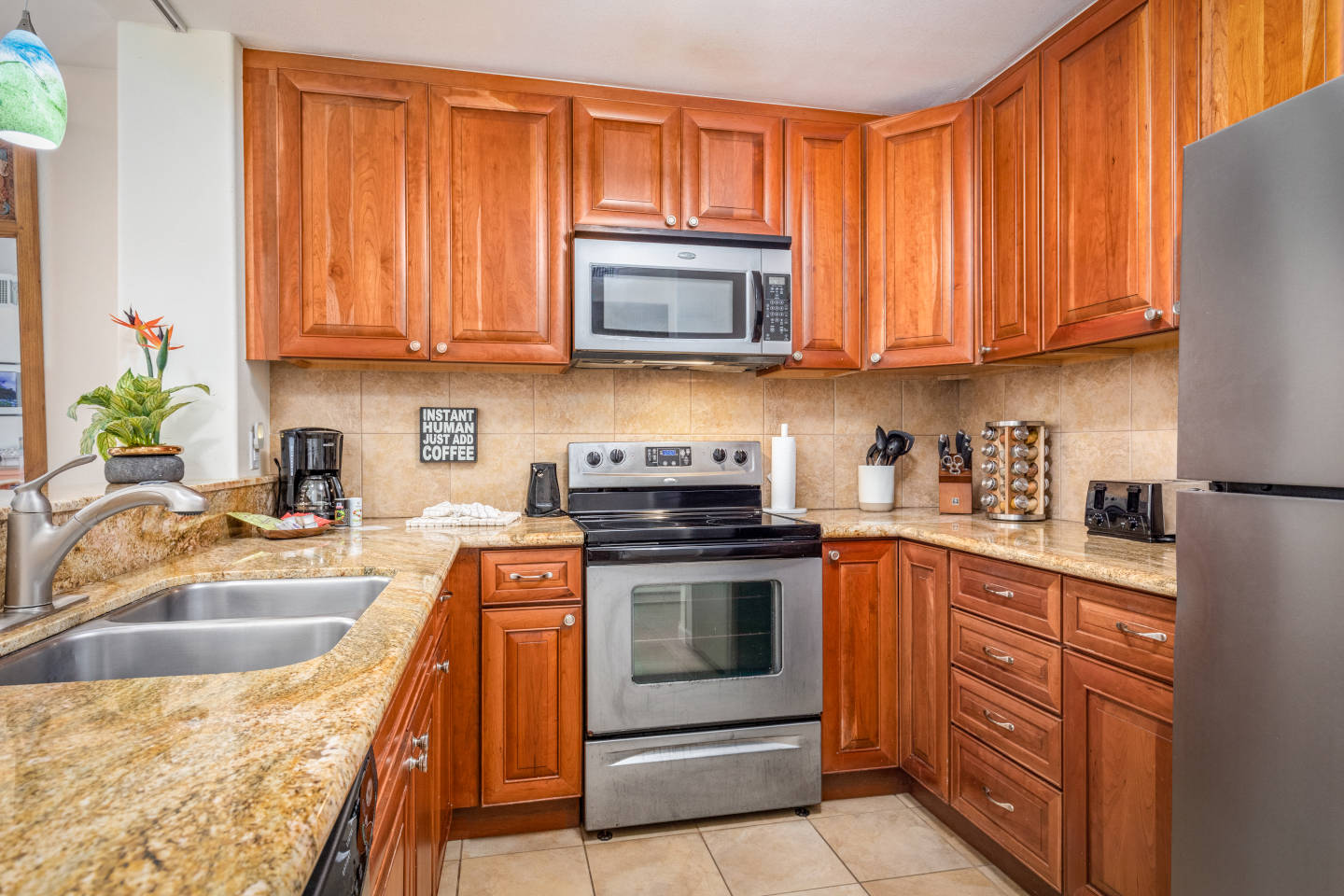 Kitchen with marble countertops, full-size stainless steel refrigerator and matching oven