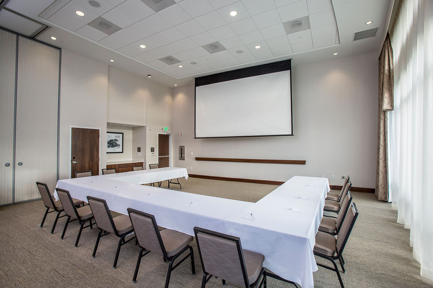 Meeting room with tables, chairs, projector scree
