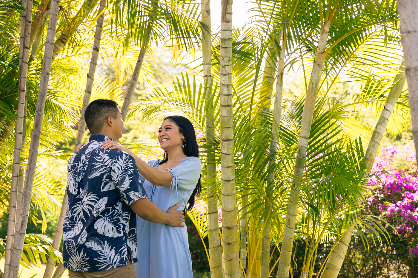 Couple embracing beneath trees in resort gardens