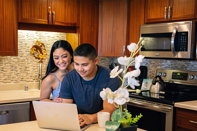 Couple in suite kitchen looking at personal laptop computer