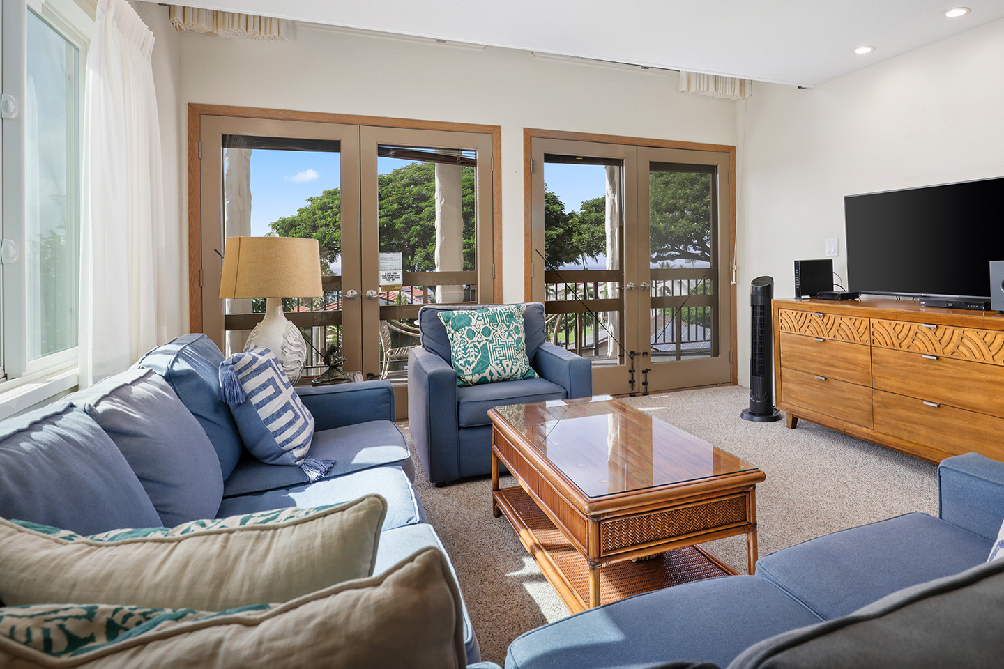 Living area with a couch, coffee table, TV, and balcony.