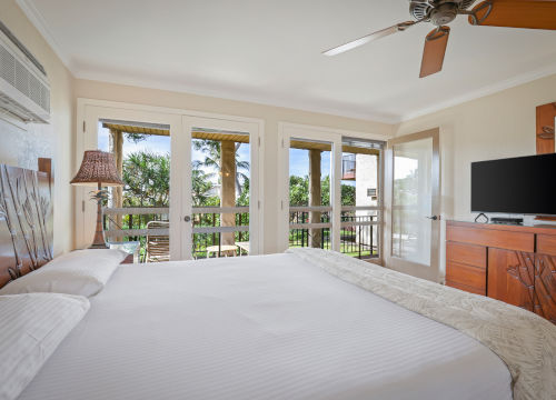 Bedroom with a bed and sliding glass doors, ceiling fan, dresser and a television
