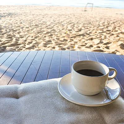 Coffee in cup and saucer on a table on the beach