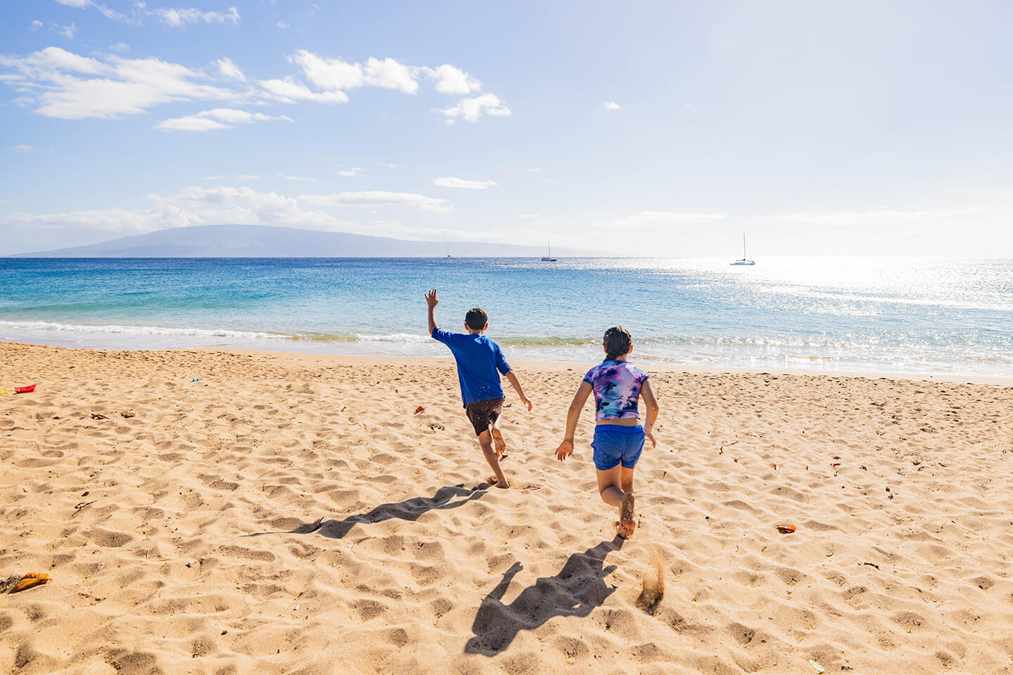 2 kids running on sandy beach