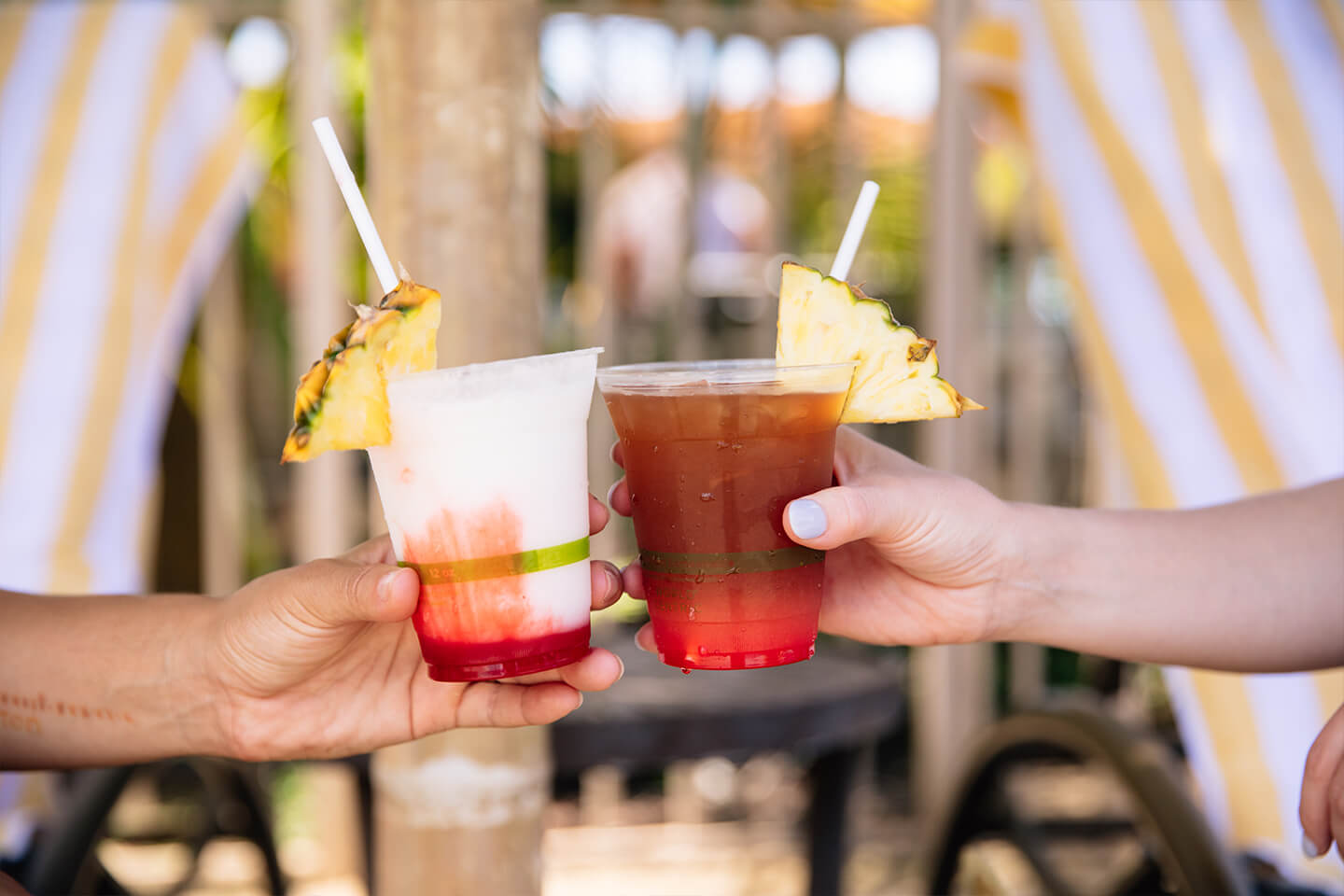 close up of 2 people toasting tropical drinks