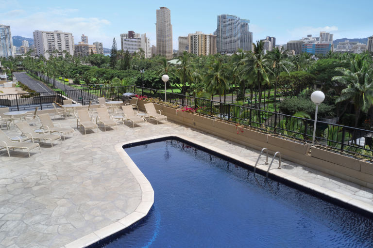 Aqua Palms Waikiki Pool deck with lounge chairs and a view of the park
