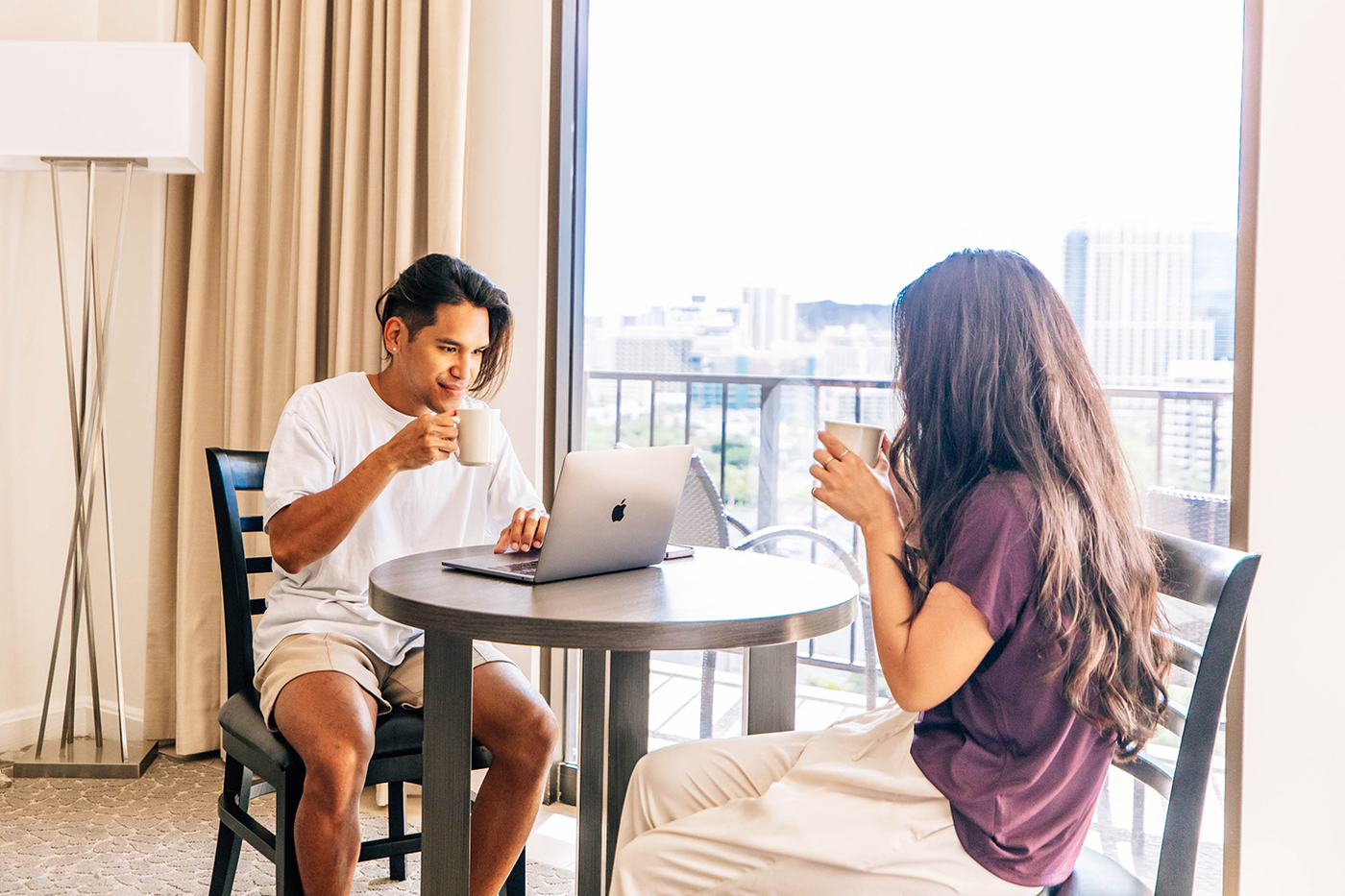 Couple sitting at table looking at computer and drinking coffee