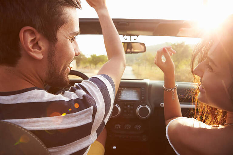 Couple riding in car with sunny background
