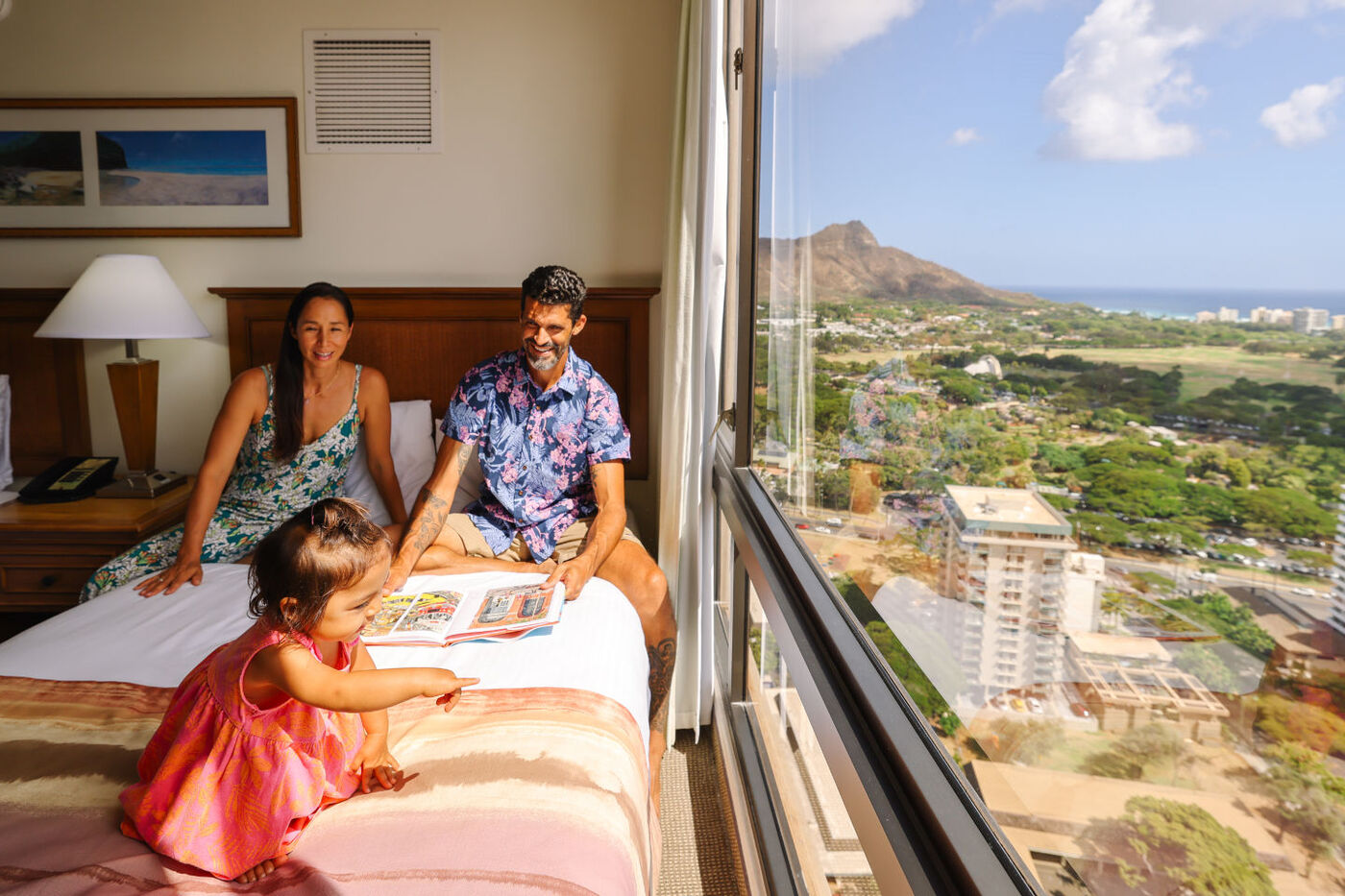 Oceanview room with family sitting on the bed near the window with a view of Diamond Head
