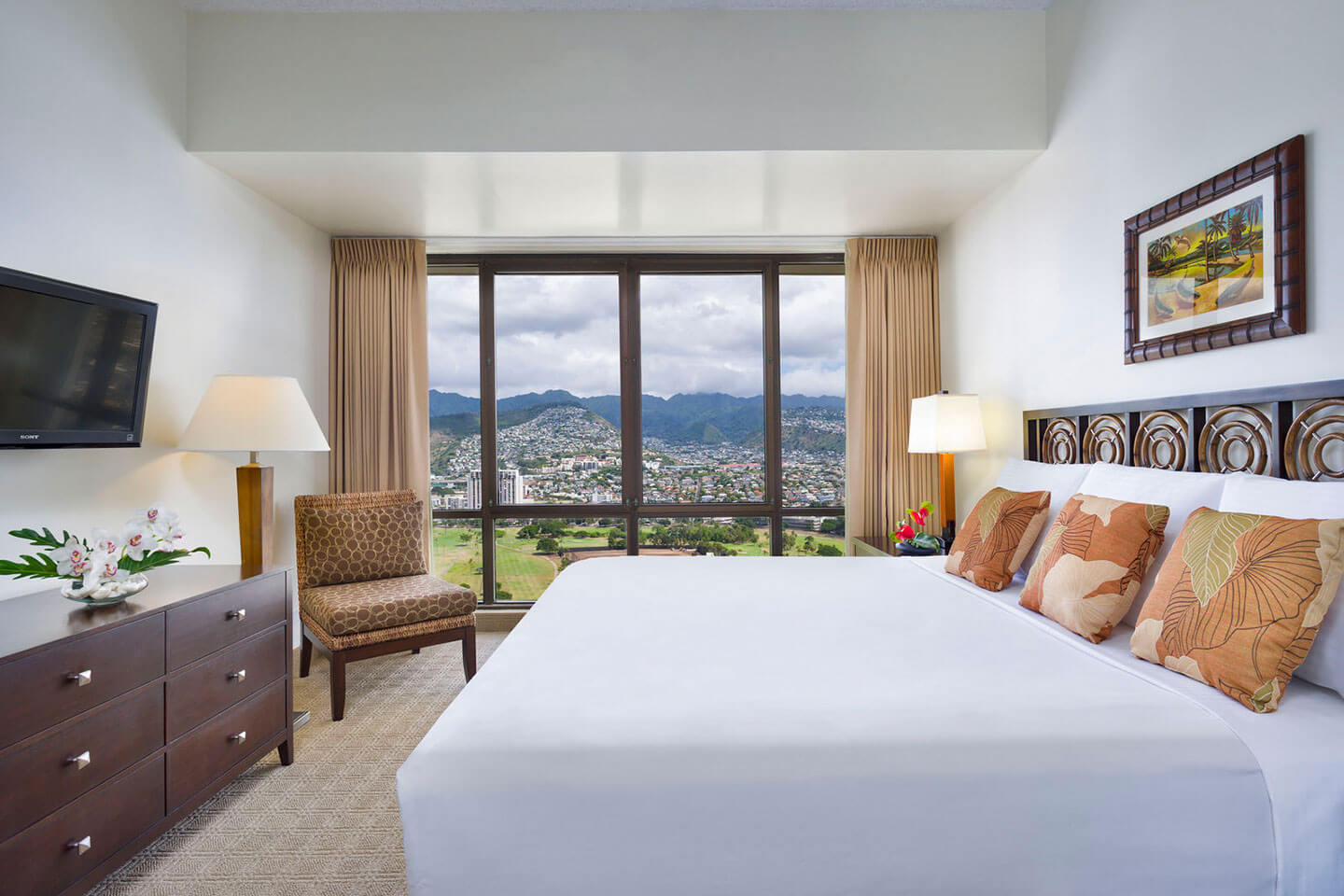 Bedroom with a bed, TV, dresser, and large picture window with mountain view.