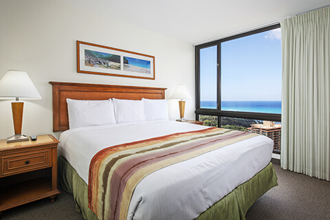 Room with bed, nightstand, lamp, large window with ocean view