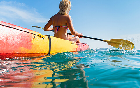 Woman paddling in a red and yellow kayak