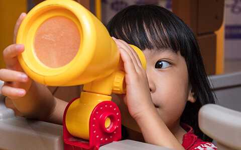 Young girl looking through toy scope