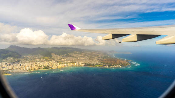 Hawaiian Airlines wing flying over Honolulu